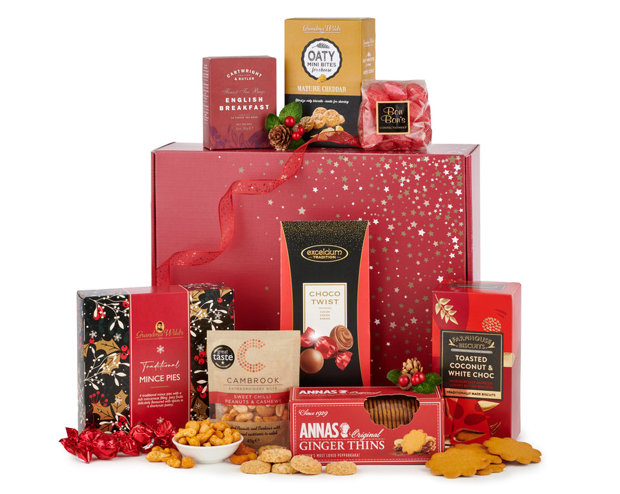 H24006 joybells christmas gift box - spicers of hythe. In a bold Christmas red colour, there's a Christmas gift box sat up, displaying all kinds of artisan food products around it. English breakfast tea, mince pies, ginger thin biscuits,cambrook nuts, chocolate twists and more are sat to display this Christmas gift box.