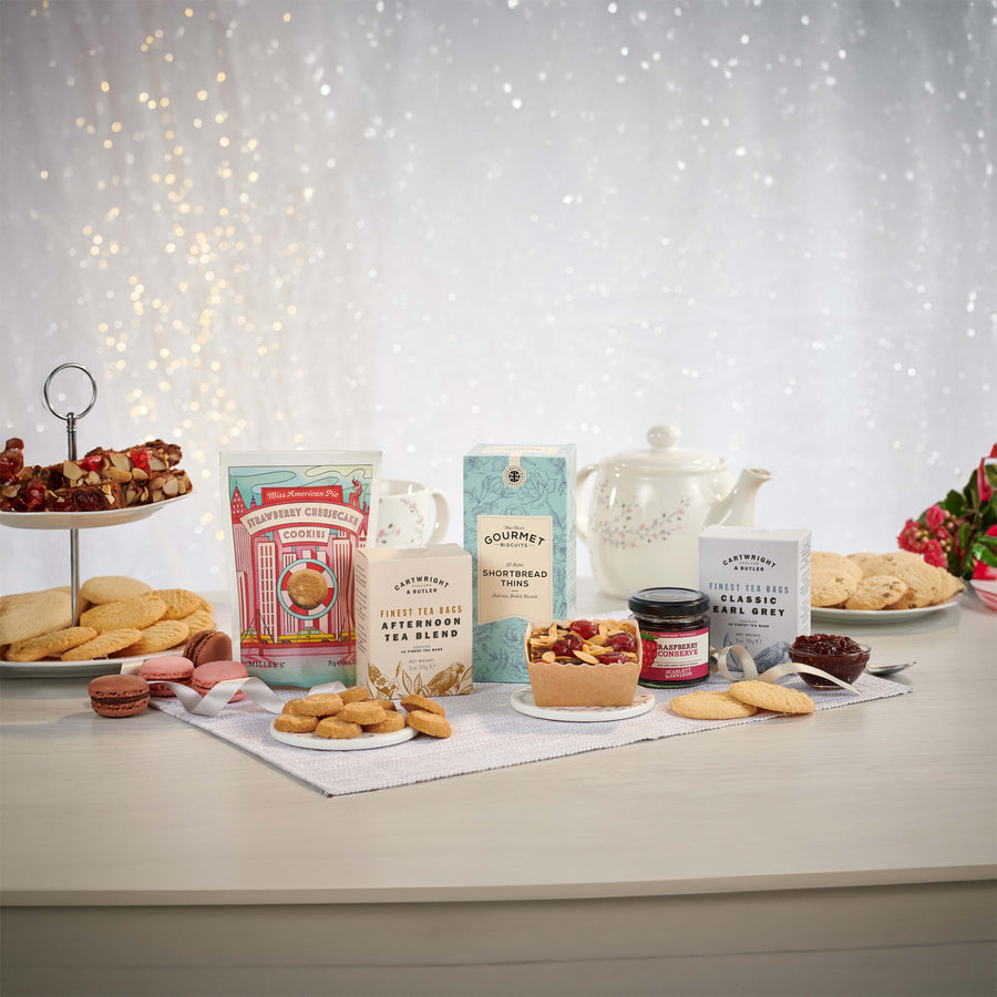 Photography of the Afternoon Tea Hamper components sat on top of the table including fruit cake, shortbread, cookies, tea pot and more.